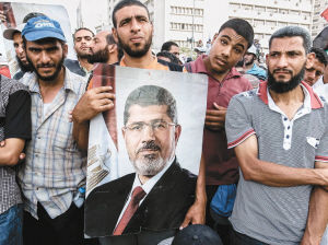 7月6日,在埃及开罗纳赛尔城的共和国卫队俱乐部外,穆尔西支持者手持穆尔西海报示威。